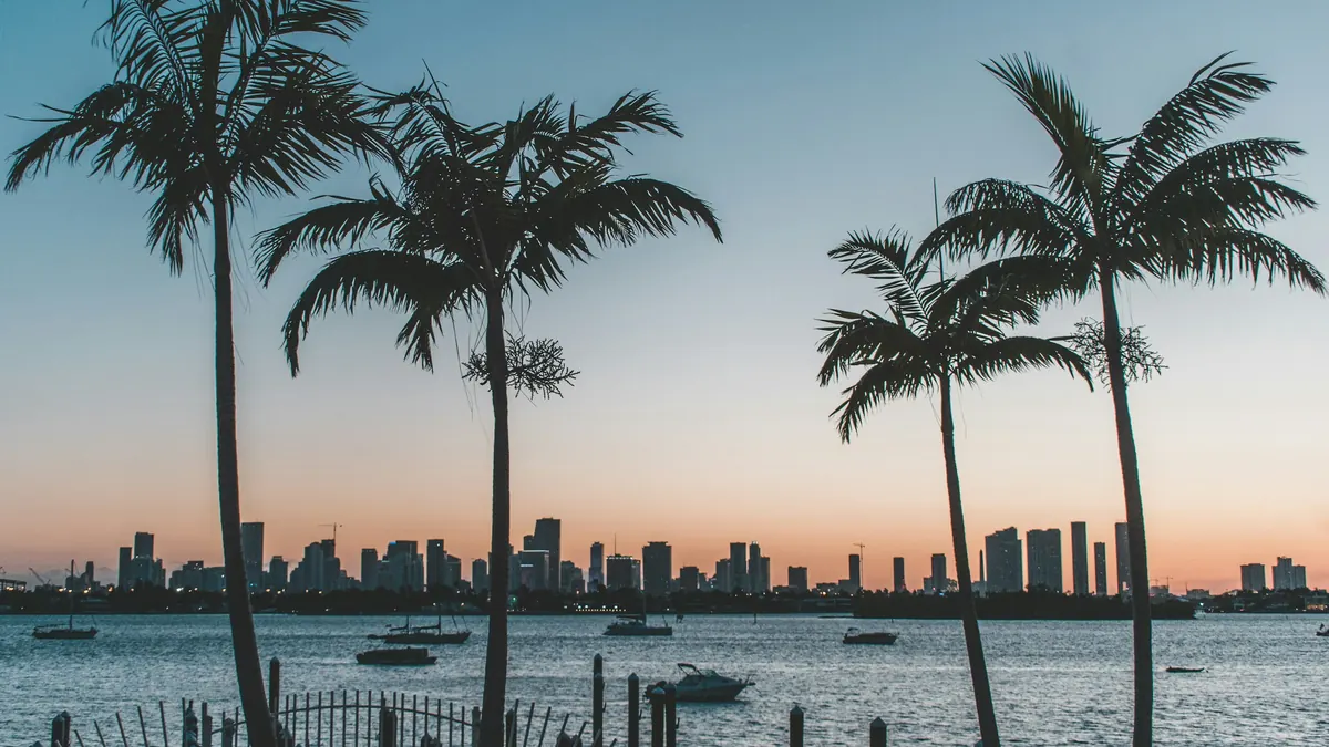 Palm trees silhouetted against a sunset over the Miami skyline